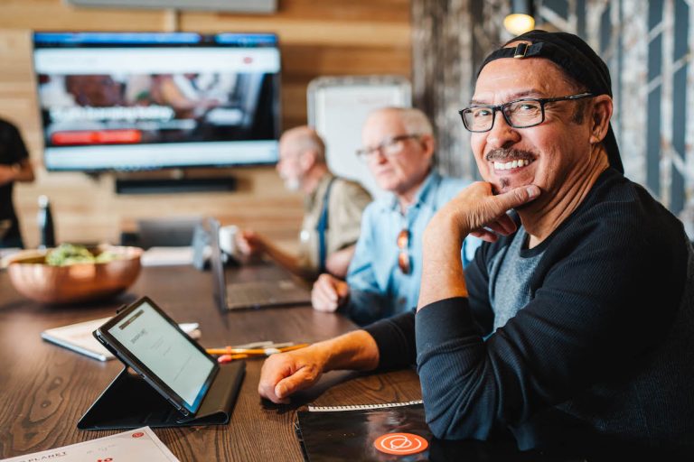 senior man in backwards hat and glasses participating in a technology class