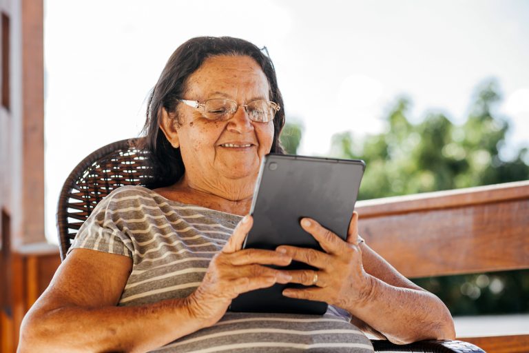 Smiling senior woman wearing glasses using digital tablet at home