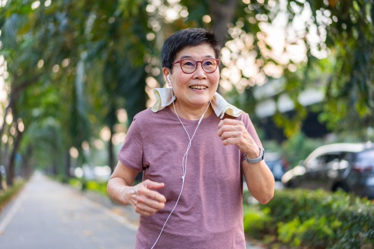 A senior woman wearing earphones while walking for exercise