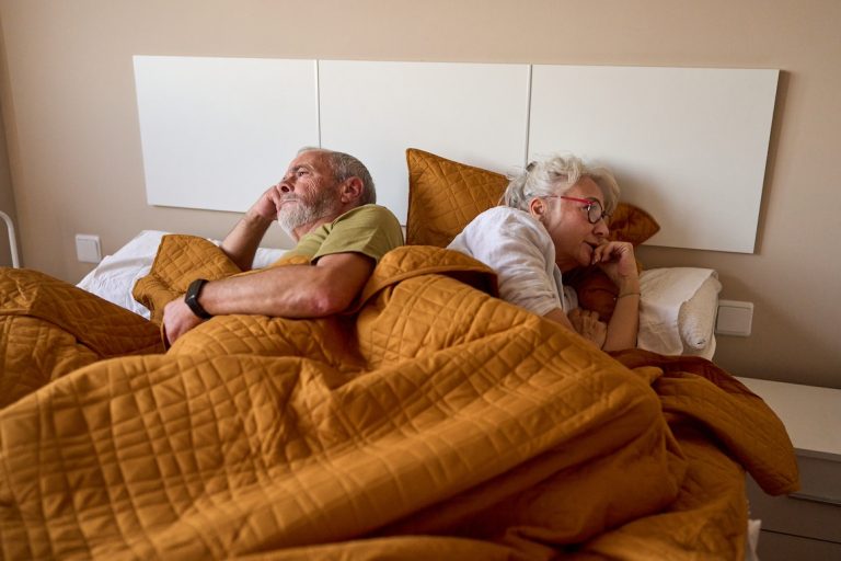 Mature couple having problems in bed, lying back to back and looking away after an argument