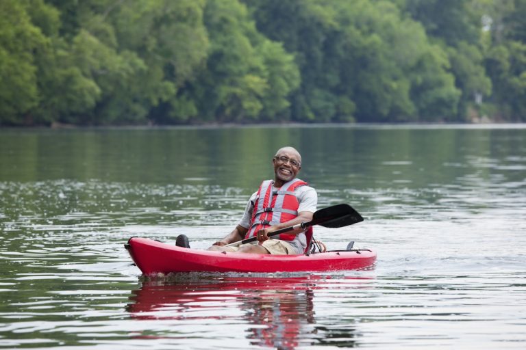 Smiling senior Black man kayaking on river