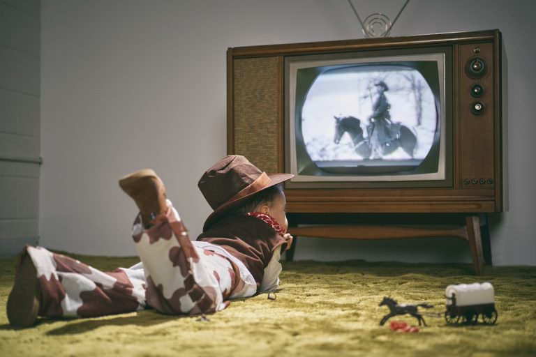 boy dressed as cowboy watching western on vintage tv set