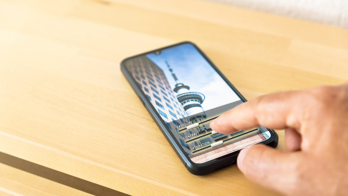 Hand editing a photo on a mobile phone. Adjusting contrast