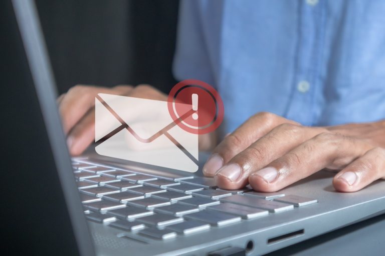 Man working on laptop with email spam notification alert with warning caution