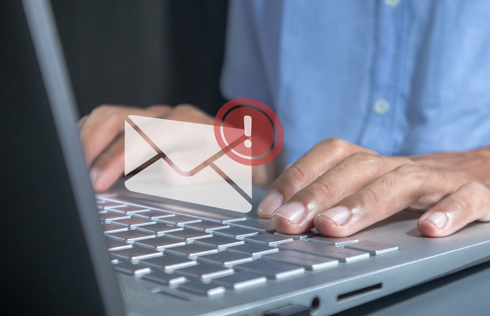 Man working on laptop with email spam notification alert with warning caution