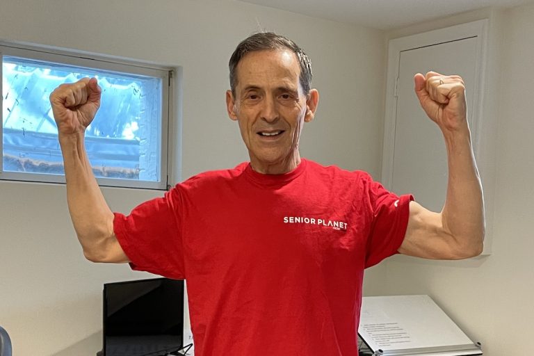 man in red Senior Planet shirt flexing arms
