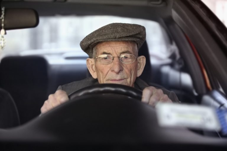 Portrait of a senior man driving a car thinking with hands on wheel