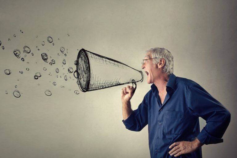 Senior man shouting into an imaginary megaphone